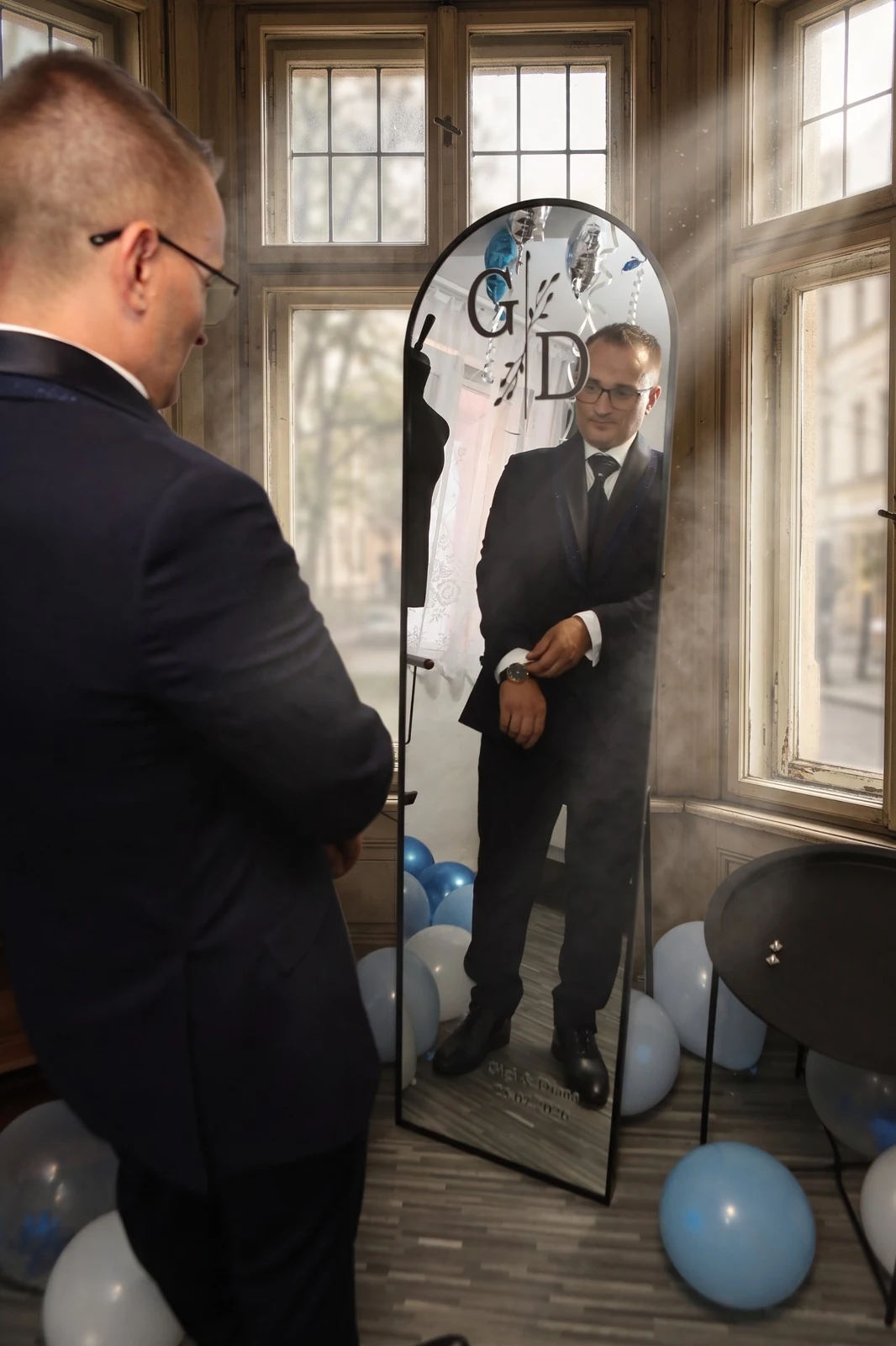 Mirele se privește într-o cabină foto oglindă, printre baloane, înainte de eveniment